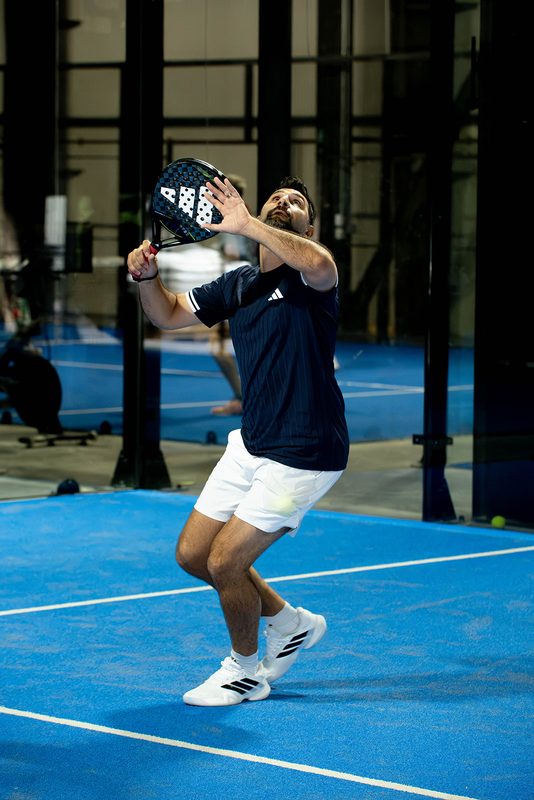 A player jumps off both feet to hit a smash at Foundry Padel