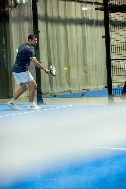 A player runs down a ball wide of the court at Foundry Padel