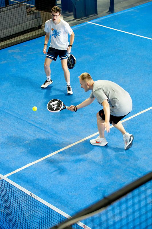 A coach demonstrates a low volley to a player
