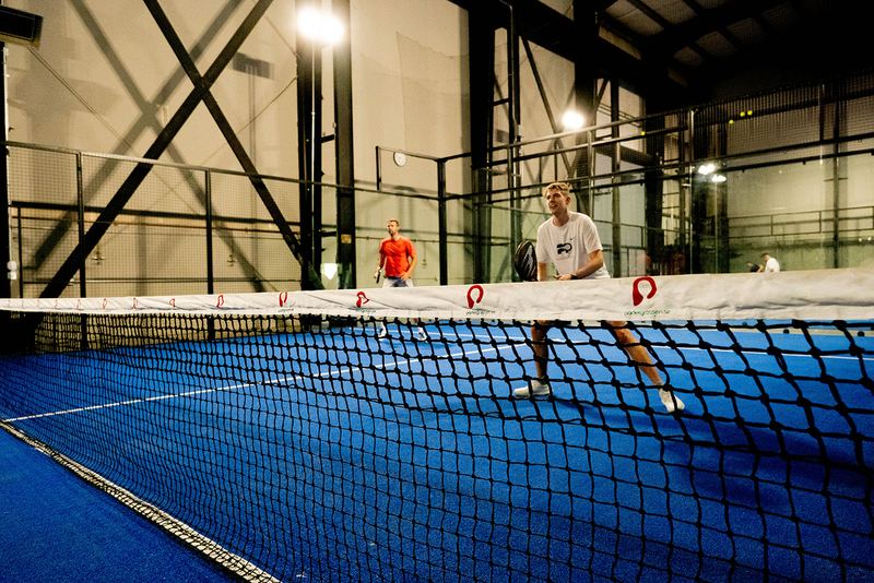 Court lights come on over an evening rally at Foundry Padel