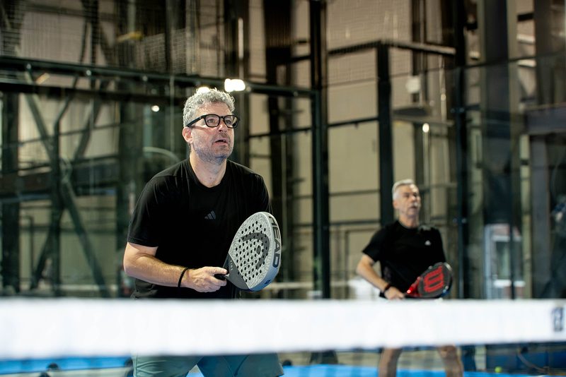 A player watches the ball from just behind the net tape at Foundry Padel