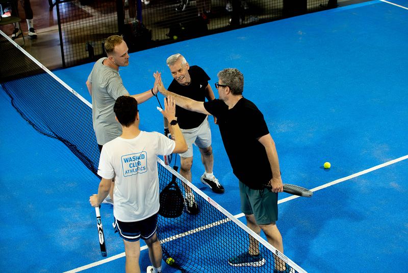 Four players high-five over the net at the end of a match