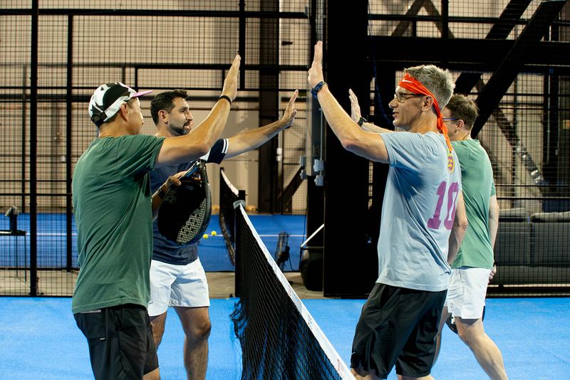 Two pairs meet at the net with hands raised after a tournament match at Foundry Padel