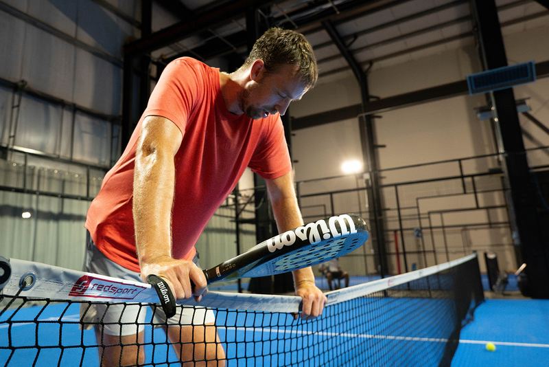 A player digs out a low volley at the net cord