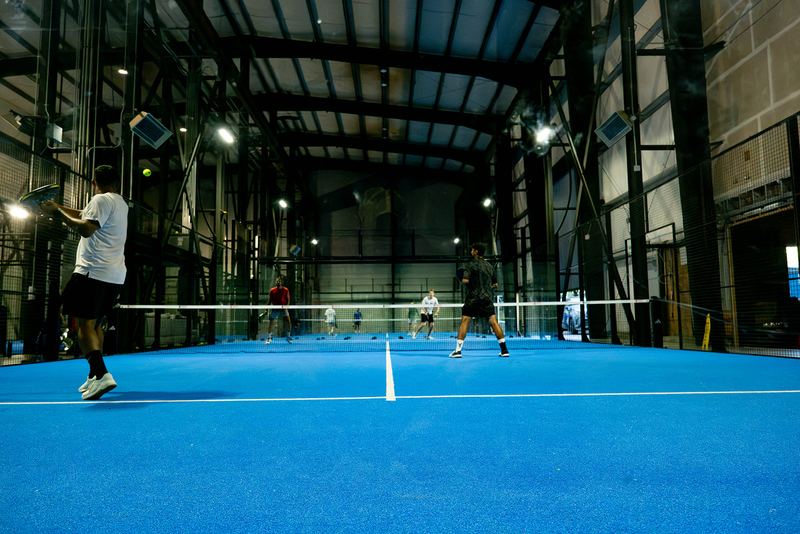 Amber light over the blue courts at Foundry Padel after dark