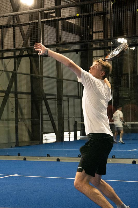A player reaches full extension on an overhead