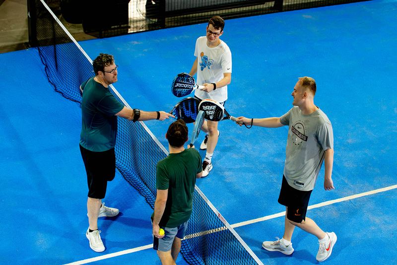Four players tap paddles across the net after a match