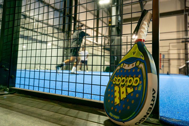 A paddle rests against the cage as play continues behind it