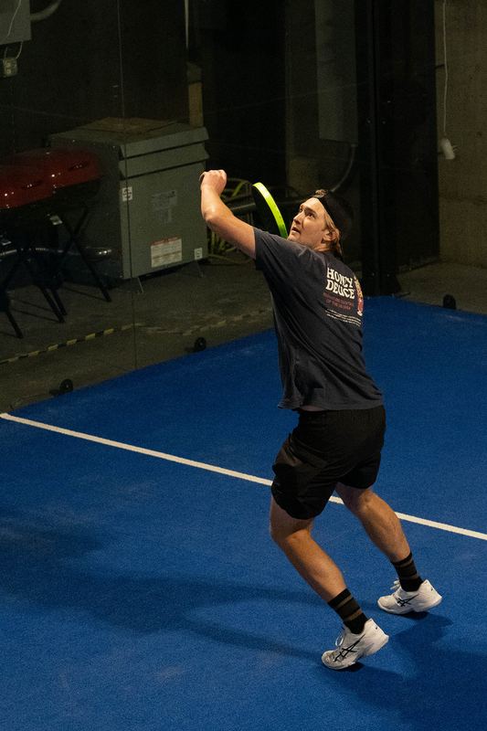 A player winds up at the top of the serve motion
