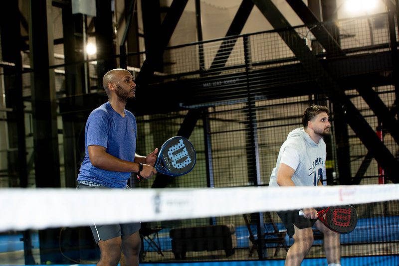 Two players lean in over the net tape to talk between points at Foundry Padel