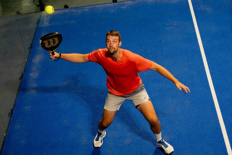 A player stretches wide for a forehand at full extension