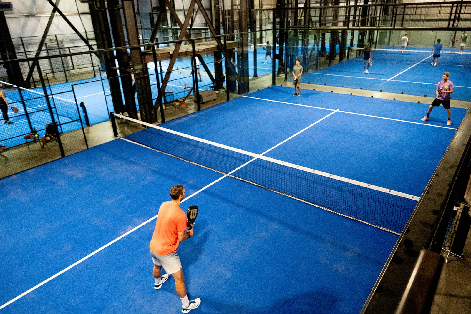 Foundry Padel's glass courts seen from above, with play underway on both