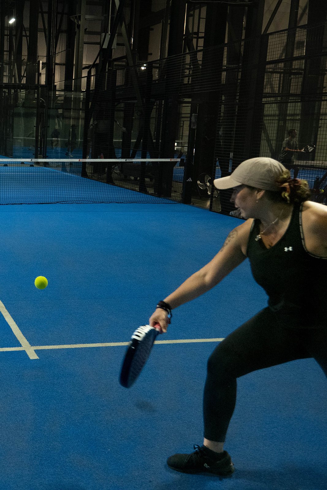 A player drops low for an underarm serve at Foundry Padel