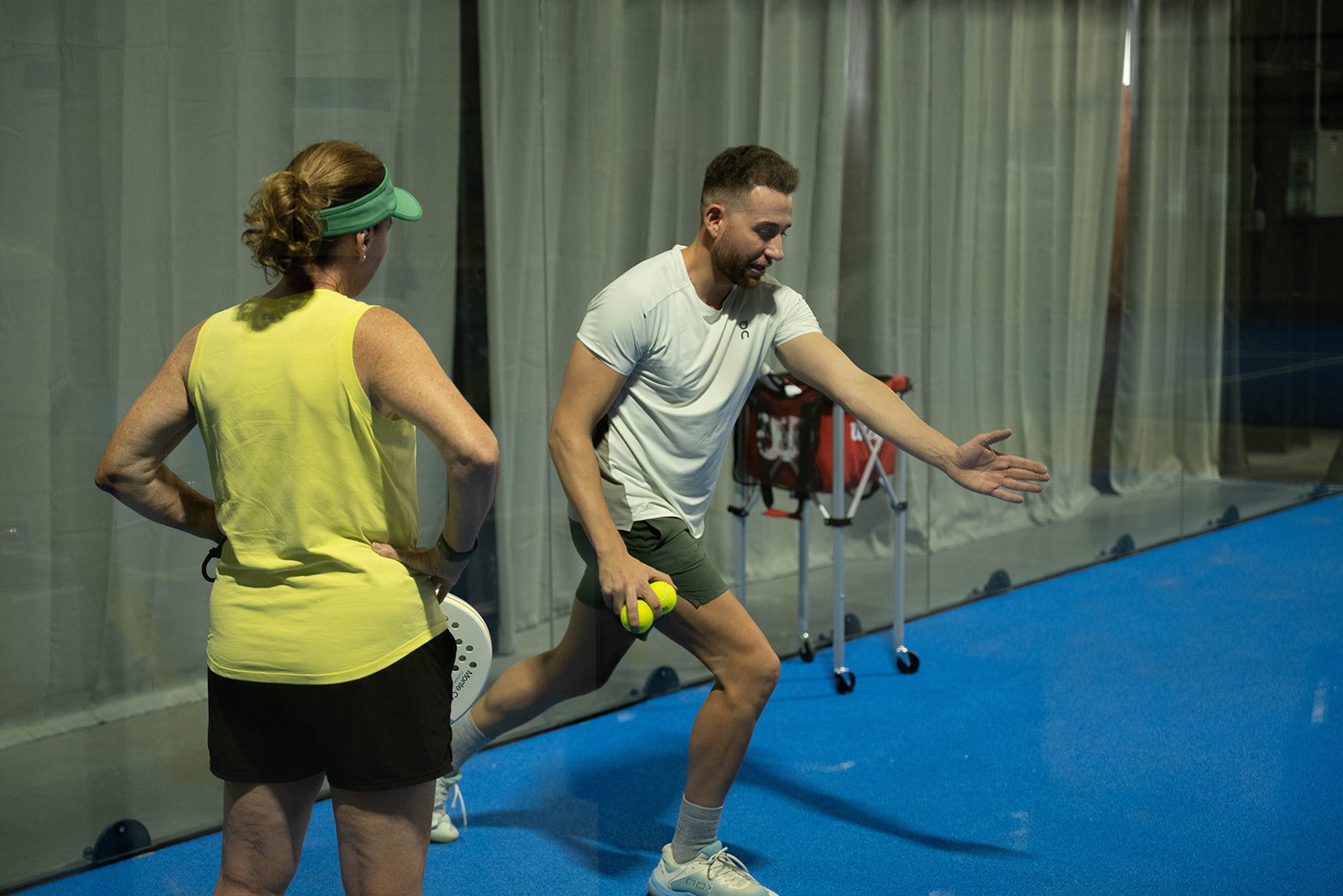 Players deep in the court by the glass back wall at Foundry Padel